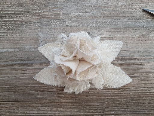 Fleur réalisée dans un tissu tissé. Elle est idéale pour orner un vêtement ou un accessoire.